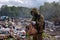 A man in a gas mask examines the contents of the bag. The worker is in the dump. Around burns and smokes plastic garbage