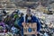 Man with gas mask holding placard, protest sign, standing standing on landfill, large pile of waste, environmental