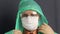 A man with a gauze face mask. He puts on safety glasses, then a protective coat. Straightens the hood with his hands. Virus