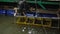 The man gets from boxes in sink water. The man on floating restaurant shows to buyers fresh seafood. Evening in Vietnam