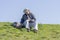 Man getting ready to fish from a grassy riverbank, sitting and l