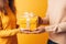 A man gives a gift in a yellow box to a woman on a yellow studio background close up