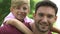 Man gives piggyback ride to son, toothy smile close-up, happy family holiday