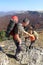 Man giving helping hand to friend to climb mountain rock cliff.