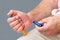 Man giving himself an insulin injection with an insulin pen to treat diabetes. on grey background