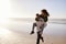 Man Giving Woman Piggyback On Winter Beach Vacation