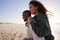 Man Giving Woman Piggyback On Winter Beach Vacation