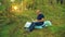 A man in glasses on a forest glade is typing on a laptop keyboard.