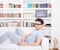 man with glasses lying on couch in front of book shelf