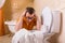 Man in glasses sits resting his hands on toilet