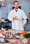 Man in glove behind counter shows fish in his hand