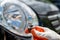 A man in a glove is holding a halogen high beam lamp near a car headlight close-up.