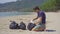 Man in gloves collects plastic trash on a beach. The problem of garbage on the beach sand caused by man-made pollution