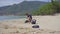 Man in gloves collects plastic trash on a beach. The problem of garbage on the beach sand caused by man-made pollution