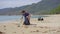 Man in gloves collects plastic trash on a beach. The problem of garbage on the beach sand caused by man-made pollution