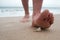 Man goes on the beach and is going to stand up on broken sharp shell.