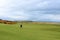 A man golfing with an incredible view of a golf hole in Scotland with the ocean in the background in Dornoch