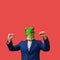 Man with googly-eyed frog mask euphoric with arms in the air celebrating on red background