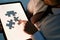 man with a graphic tablet is collecting a puzzle while sitting at his desk .