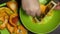 A man grates slices of orange pumpkin. Close-up shot from above