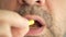 A man with a gray beard swallows a pill from the virus, coronavirus, and makes a wry face. Super macro close-up.