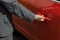 Man in a gray checked suit opens the door of a red car