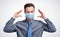 Man in a gray shirt and tie puts a respiratory mask on his face. Virus protection concept