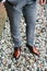 Man in a gray suit and brown shoes stands on stone surface. Male feet in brown leather shoes close up. Selective focus.