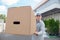 A man in a gray suit in his hands with a cardboard box against the background of the supermarket. Concept on the topic of postal