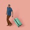 Man with green plastic suitcase posing in studio on pink background. Elegance Caucasian man in blue t-shirt and brown