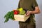 Man in green t-shirt holding wooden box full of vegetable