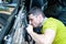 A man in a green t-shirt intently disassembles a car door in order to repair a power window. Car repair at a service station