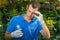 A man in a greenhouse examines a test tube with a liquid for fertilizing plants