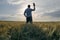 A man greets the dawn on the field with his hat raised in greeting