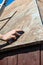 Man grinding the roof of a garden shed with a sanding block, rust and weathered