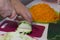 A man grinds a vegetable marrow. Nearby vegetables for cooking squash caviar. Zucchini, carrots, onions and tomatoes on the table