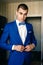 The man, the groom in a classic blue suit against the background of the apartment. Wedding, groom, family creation