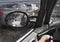 Man with gun in car with police car in sideview mirror