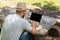 Man or guy working on a computer with a blank screen for copy space, sitting on a bench in the summer outdoors