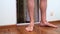 Man with hairy legs in shorts barefoot crosses the threshold, enters the balcony of a Flat, scratches his leg.