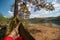 Man in hammock, first person look view, warm summer day, pine tree. river and mountains background. Travel and vacation, tourism