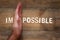 man hand dividing the letters IM from the word impossible so it