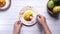 Man hand eating yellow ripe cut mango from plate, top down.