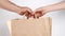 Man hand give craft food paper bag to woman hands