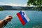 Man hand hold slovenian flag against view of beautiful Bled Lake, Slovenia