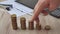 Man hand holding coin dollar on money coin stack arranged as a graph on wooden table. Hand of male or female finger step