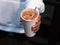 Man hand holding disposable white recycling glass of cold cappuccino coffee