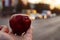 Man hand holding and giving big red apple on traffic cars background with copy space for text. Concept of proper diet. Fresh and