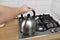 Man hand holding metalic kettle in the kitchen. Kettle use hot water to boil drinks such as tea, coffee, milk powder