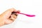 Man hand is holding the pink color of plastic long spoon